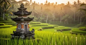 Tradycyjna kamienna kapliczka na tle soczyście zielonych tarasów ryżowych w Ubud o zachodzie słońca.